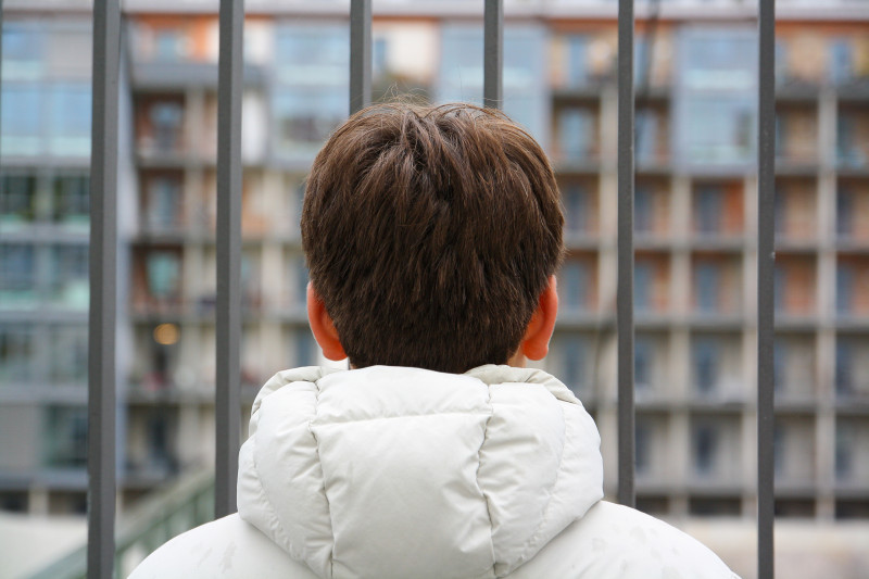 eine Junge von hinten fotogarfiert blickt auf eine Häuserfassade