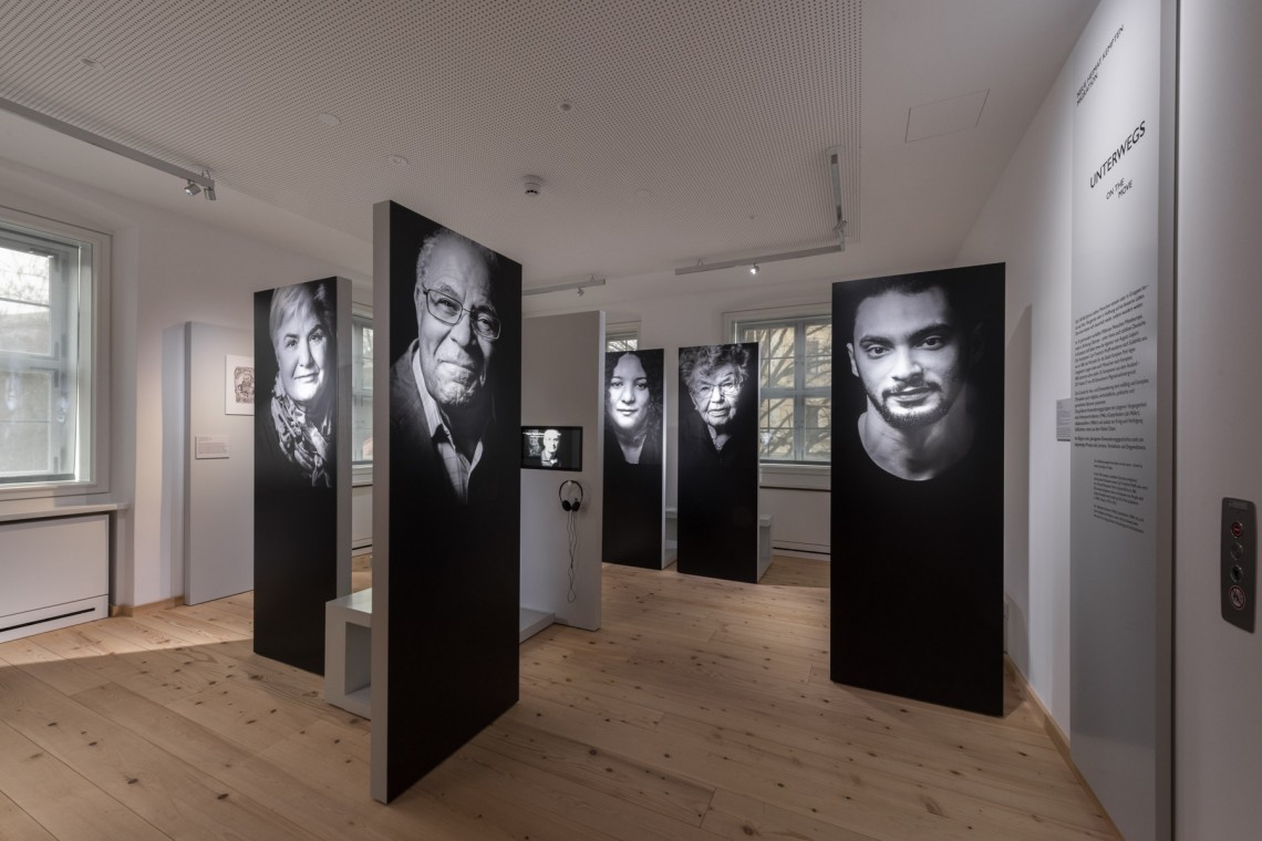 Schwarze Stehlen mit großen Schwarz-Weiß-Portraitfotos im Raum &quot;Migration&quot; des Kempten-Museums