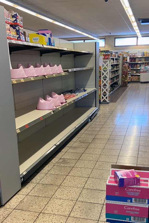 wenige Töpfchen und Regenschirme stehen in sonst leerem Klopapierregal in Supermarkt