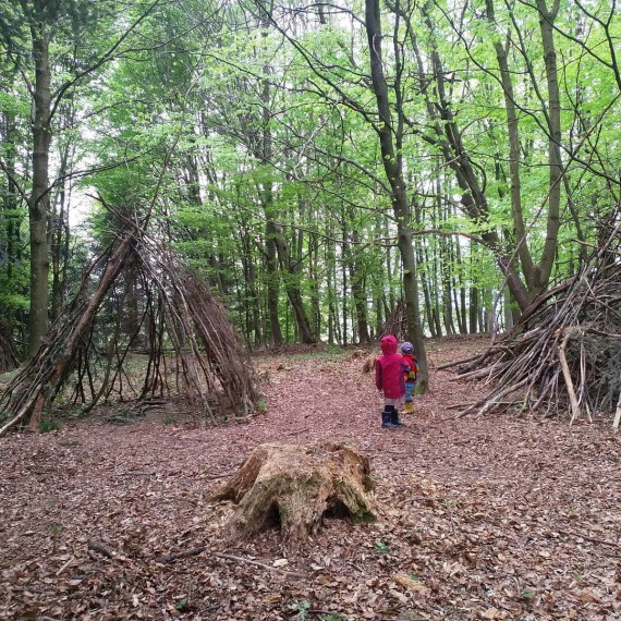 Zwei Tipis aus Ästen in Wald, zwei Kleinkinder