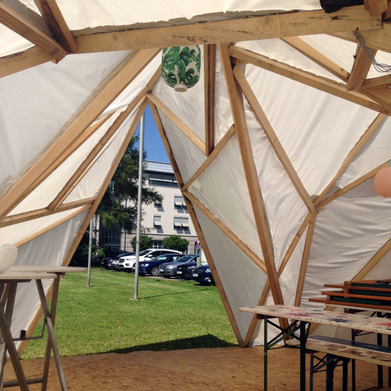 Zeitkonstruktion aus geomatrisch angeordneten Holzbalken und weißem Tuch