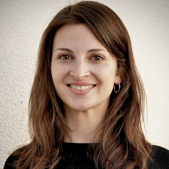 junge Frau mit langen braunen Haaren lächelt in die Kamera