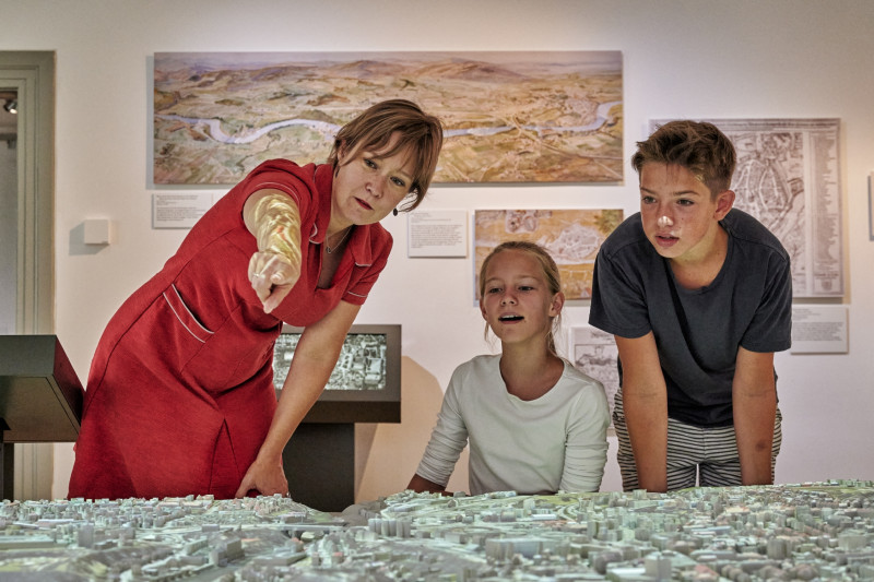 Woman, girl and boy look at the 3D city model of Kempten