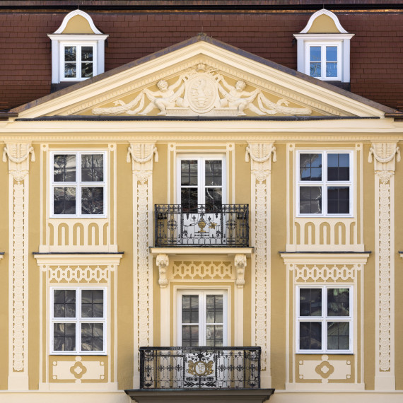 ocker-farbene Hausfront mit zwei Balkonen