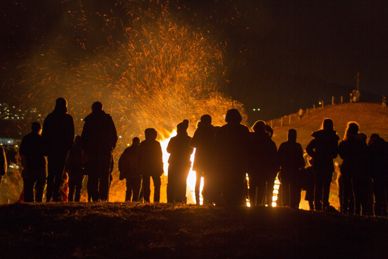 Menschen stehen nachts vor einem brennenden Feuer