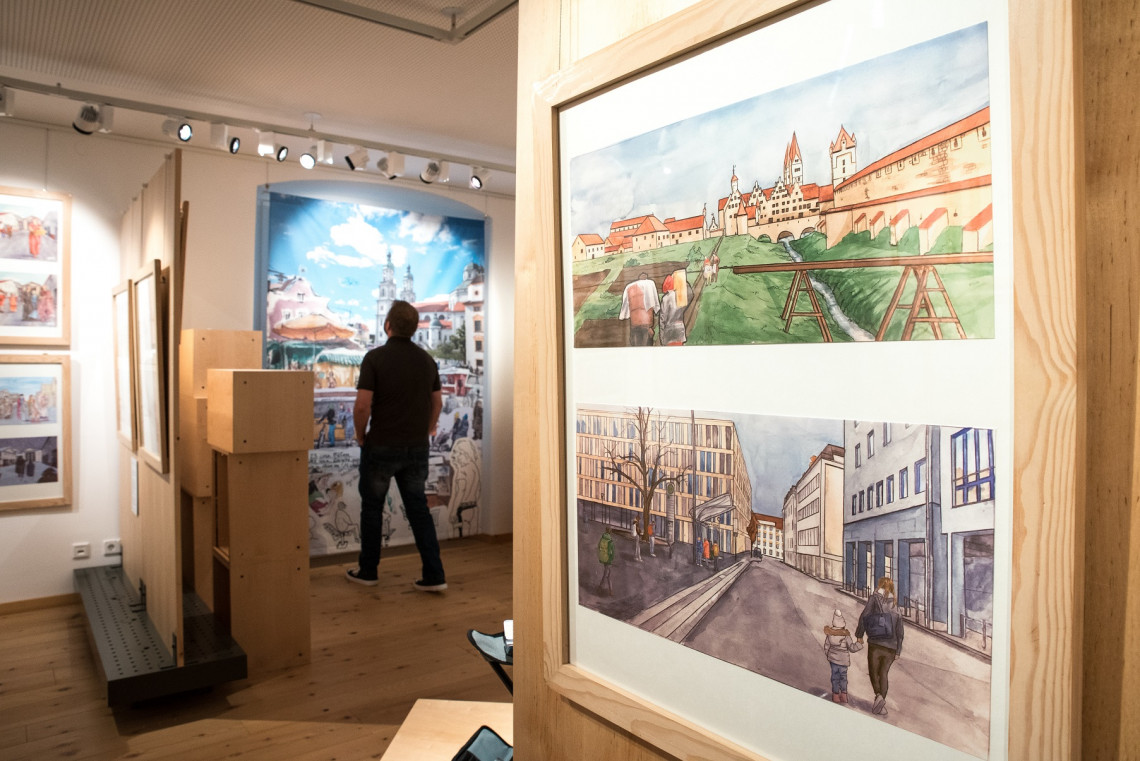Blick in Ausstellung mit Zeichnungen an Stellwänden und Besucher