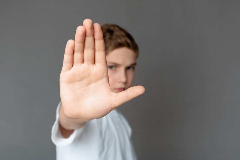 ein Junge hält abwehrend eine Hand in die Kamera